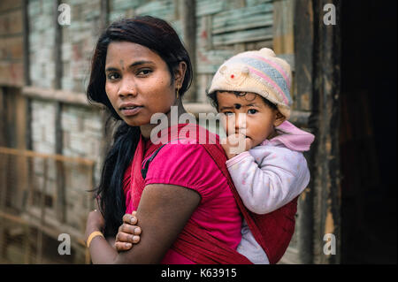 Ambulante Straße Bauarbeiter mit Kind auf dem Rücken auf der Autobahn nächste shanty Bambushütte in Arunachal Pradesh, Indien am Straßenrand. Stockfoto