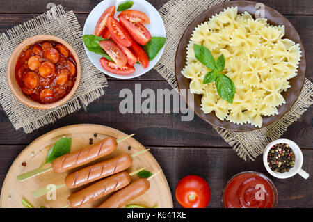 Farfalle Nudeln, Würstchen am Spieß, frische Tomaten, würzige Tomatensauce mit Stücken von Wurst. Italienische Küche. Stockfoto