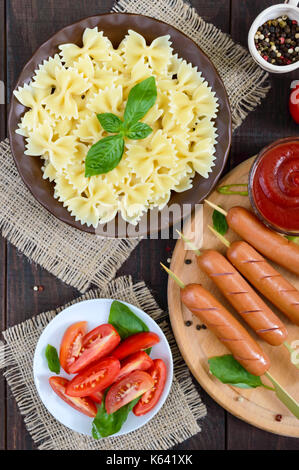 Farfalle Nudeln, Würstchen am Spieß, frische Tomaten, würzige Tomatensauce. Italienische Küche. Stockfoto