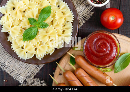 Farfalle Nudeln, Würstchen am Spieß, pikanter Tomatensauce. Italienische Küche. Stockfoto