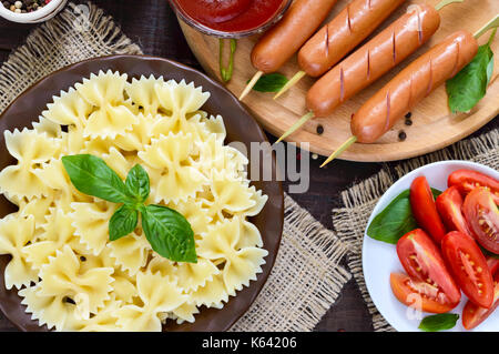 Farfalle Nudeln, Würstchen am Spieß, frischen Tomaten. Italienische Küche. Stockfoto