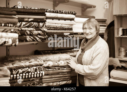 Reife Frau wählt Gewebe im Stoffladen Stockfoto