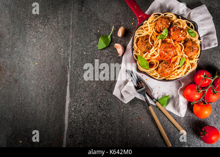 Spaghetti Nudeln mit Hackfleischbällchen, Tomatensauce Basilikum in Rot gusseisernen Pfanne, auf schwarzen Stein Tabelle kopieren Raum, Ansicht von oben Stockfoto