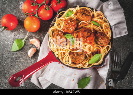 Spaghetti Nudeln mit Hackfleischbällchen, Tomatensauce Basilikum in Rot gusseisernen Pfanne, auf schwarzen Stein Tabelle kopieren Raum, Ansicht von oben Stockfoto