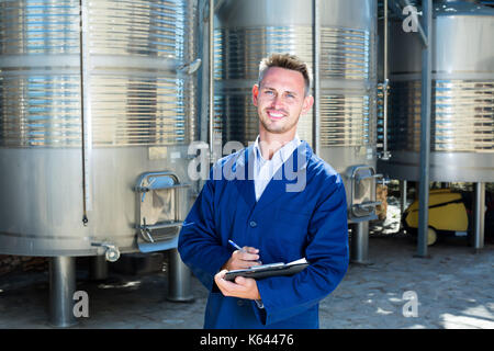 Portrait von Mann Weingut Arbeiter stehen auf Wein Fabrik in sekundären Gärung Abschnitt Stockfoto