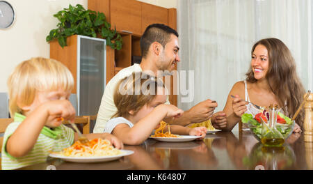 Positive junge Familie von vier essen Spaghetti zu Hause Interieur. Fokus auf den Menschen Stockfoto