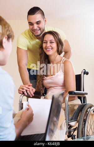 Schöner Mann und behinderte Frau im Rollstuhl im Gespräch mit der sozialarbeiterin Stockfoto