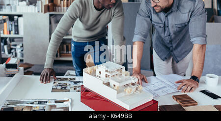 Architekten der Vorbereitung neuer Gehäuse Projekt. Zwei junge Mann von ihren Schreibtisch mit einem architektonischen Haus Modell. Stockfoto