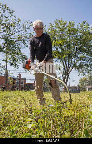 Detroit, Michigan - Personen mit Wohnsitz in der Gemeinschaft und die Mitglieder der Knights of Columbus sauber Papierkorb und Bürste aus Baulücken in der Morningside Nachbarschaft. Stockfoto