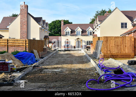 Baustelle für neue kleine Wohneigentum Entwicklung kurz vor dem Abschluss mit Aufkantungen Gartenzäune und Straße Stiftungen in Fortschritte Essex England Großbritannien Stockfoto