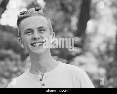 Kaukasischen jungen Mann mit blauen runde Sonnenbrille auf der Stirn lächelnd Stockfoto