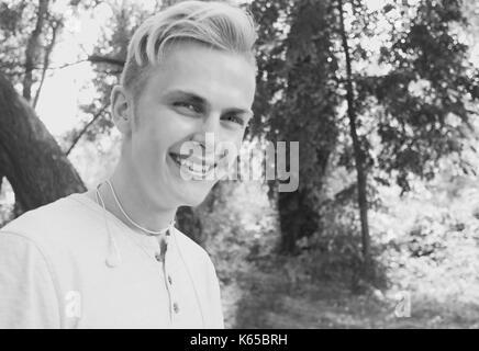 Kaukasischen jungen Mann mit blauen runde Sonnenbrille auf der Stirn lächelnd Stockfoto