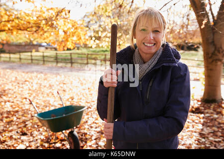 Portrait von reife Frau Harken Blätter im Herbst im Garten Stockfoto