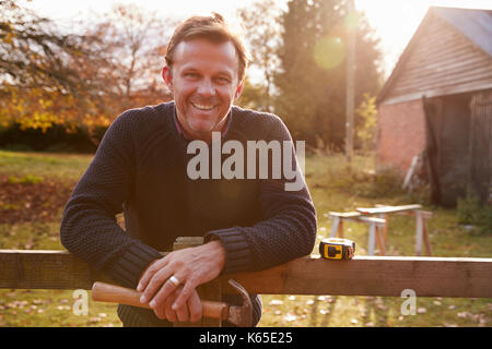 Portrait von reifer Mann reparieren Gartenzaun Stockfoto