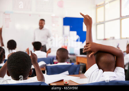 Kinder heben die Hände Lehrer an einer Volksschule Lektion zu beantworten Stockfoto