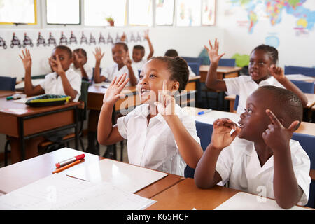 Kinder, die Hände im Unterricht an einer Volksschule Stockfoto