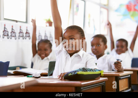 Kinder heben die Hände während einer Lektion an einer Volksschule Stockfoto