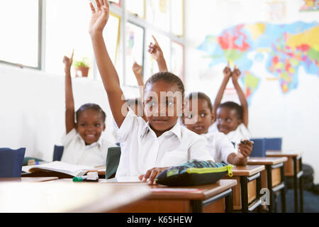 Kinder heben die Hände während einer Lektion an einer Volksschule Stockfoto