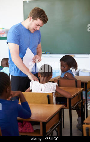 Weiße männliche Lehrer Schülerinnen helfen in der Grundschule Stockfoto