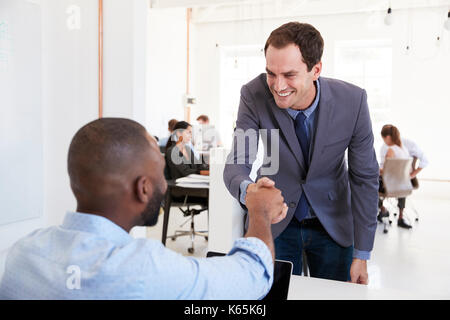 Zwei Männer die Hände schütteln bei einem Treffen in einem Großraumbüro Stockfoto