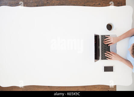 Junge Frau am Schreibtisch sitzen und tippen auf Laptop Stockfoto