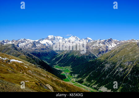 Blick auf das Tal von Livigno Stadt mit der Bernina Berge in der Ferne Stockfoto