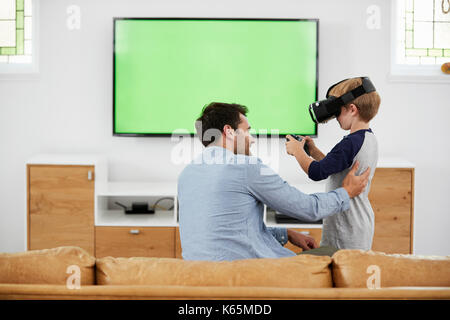 Vater und Sohn spielen Computer Spiel mit Virtual Reality Headset Stockfoto