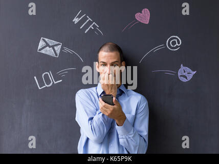 Konzept der sozialen Medien chat. Einzelne weiße erwachsenen Mann, der vor einer Tafel mit seinem Smart Phone. Stockfoto