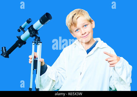 Kind die Schule junge mit astronomischen Teleskop. Auf blau keying Hintergrund isoliert. Konzept der kleinen Wissenschaftler tragen weiße wissenschaftlichen Anstrich. Stockfoto