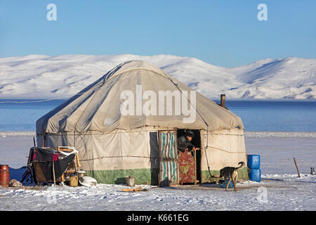 Kirgisischer Mann in Türöffnung der traditionellen Jurte im Schnee entlang Song Kul / Song Kol See im Tian Shan Gebirge, Provinz Naryn, Kirgisistan Stockfoto