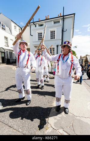 Tradition Morris Dancers, Hartley Morris Seite, stehend in 2 Zeilen in der Straße, die Holzpfähle. Alle weiße Uniform mit roten Klammern und Strohhut. Stockfoto