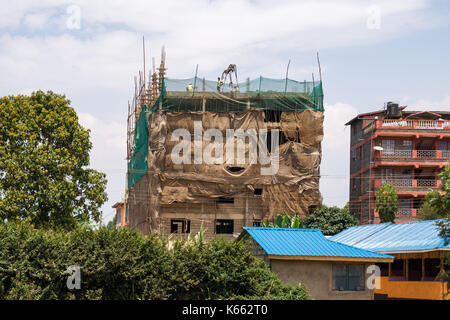 Appartementhaus im Bau mit Bauarbeiter auf dem Dach in der kleinen Stadt, Kenia Stockfoto