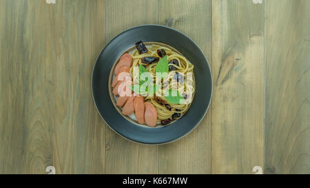 Spaghetti mit Wurst und getrocknete Paprika, würzig und scharf auf hölzernen Hintergrund, Ansicht von oben Stockfoto