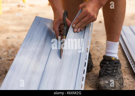 Ein Bauarbeiter durch Vinylabstellgleis mit heavy duty Schere in Ontario, Kanada. Stockfoto