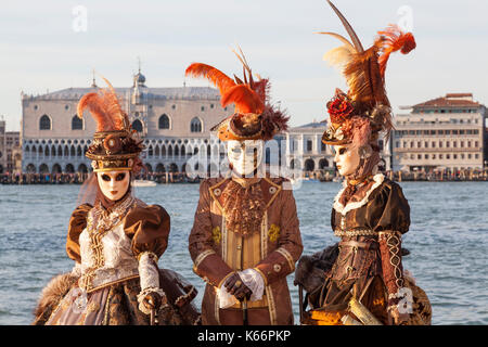 2017 Karneval, Venedig, Italien. Drei Menschen in der klassischen Wiederbelebung Kostüme Stellen in San Girgio Maggiore mit den Dogenpalast und die Lagune hinter Ihnen bei s Stockfoto