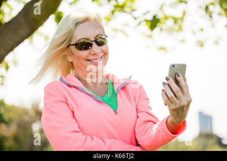 Wind die Haare der kaukasischen Frau SMS auf Handy Stockfoto