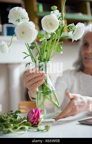 Ältere Frau Blumen arrangieren Stockfoto