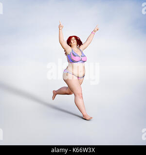 Übergewichtige Frau im Bikini läuft Stockfoto