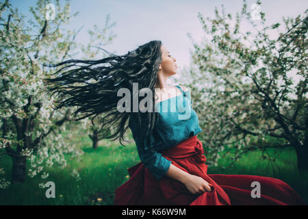 Kaukasische Frau Haar warf in der Nähe von blühenden Bäumen Stockfoto