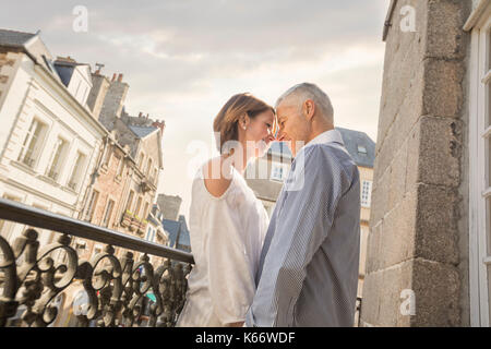Kaukasische Paar reiben Sie Ihre Nasen auf dem Balkon in der Stadt Stockfoto