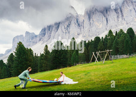 Brücke und Bräutigam Spaziergang auf der Wiese von Alto Adige/Südtirol mit atemberaubenden Dolomiten im Hintergrund Stockfoto