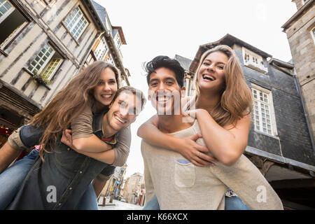 Männer, die Frauen Huckepack in Stadt Stockfoto