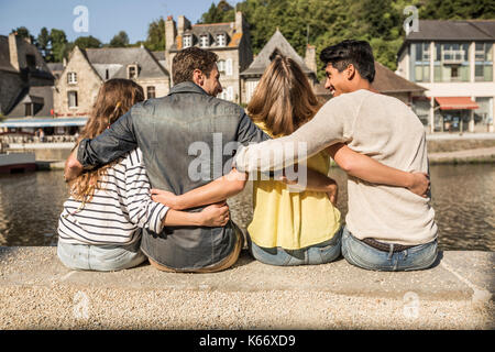 Freunde sitzen und Umarmen im Waterfront Stockfoto