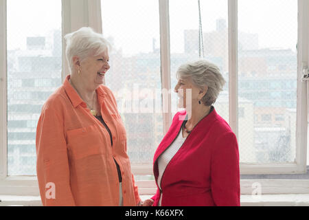 Ältere kaukasischen Frauen Lachen in der Nähe der Fenster Stockfoto