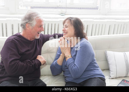 Älteres Paar sitzt auf dem Sofa und Lachen Stockfoto