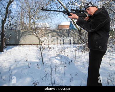 Mann mit einem Luftgewehr in einem Winter Park Stockfoto