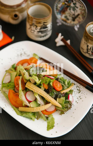 Stäbchen auf Teller mit Salat Stockfoto