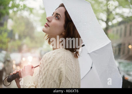 Kaukasische Frau mit Regenschirm suchen Stockfoto