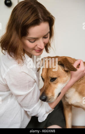 Kaukasische Frau umarmt Hund Stockfoto