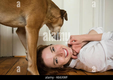Hund stehend über kaukasische Frau Festlegung auf dem Boden Stockfoto